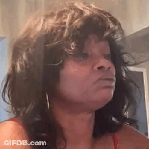 A Woman With Curly Hair Is Making A Funny Face And Looking At The Camera . GIF