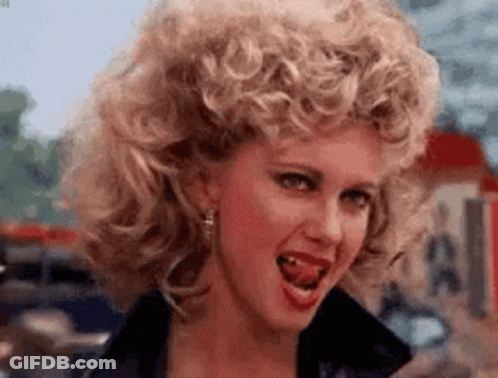 A Woman With Curly Hair Is Making A Funny Face With Her Tongue Hanging Out . GIF
