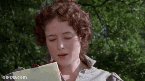 A Woman With Curly Hair Is Reading A Book In Front Of Trees . GIF
