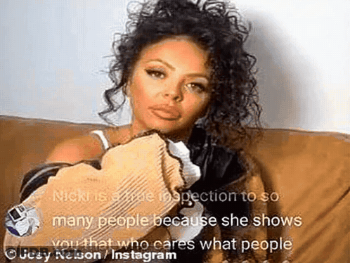 A Woman With Curly Hair Is Sitting On A Couch And Holding A Piece Of Paper . GIF
