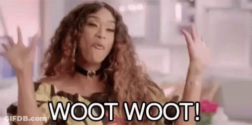 A Woman With Curly Hair Is Sitting On A Couch With Her Hands In The Air . GIF