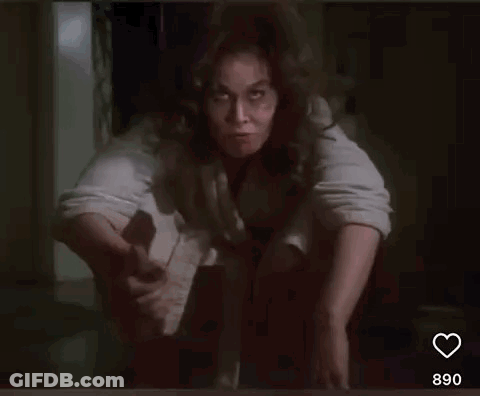 A Woman With Curly Hair Is Sitting On The Floor And Smiling . GIF