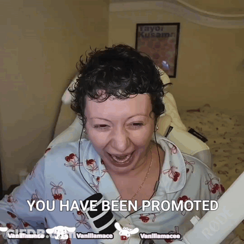 A Woman With Curly Hair Is Smiling And Holding A Microphone With The Words " You Have Been Promoted " Above Her GIF