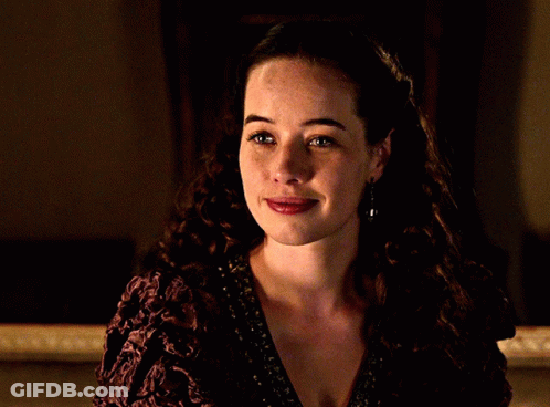 A Woman With Curly Hair Is Smiling And Wearing A Purple Dress GIF