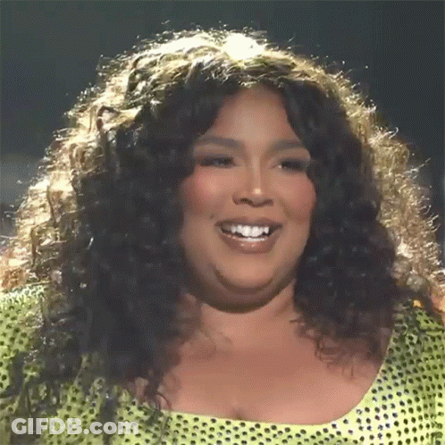A Woman With Curly Hair Is Smiling And Wearing A Yellow Top With Polka Dots GIF