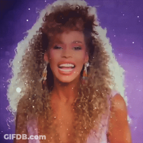A Woman With Curly Hair Is Smiling And Wearing Earrings GIF