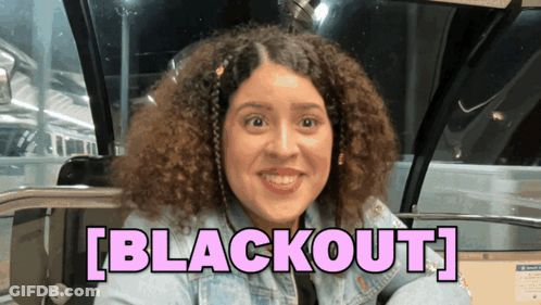 A Woman With Curly Hair Is Smiling In Front Of A Sign That Says " Blackout " GIF