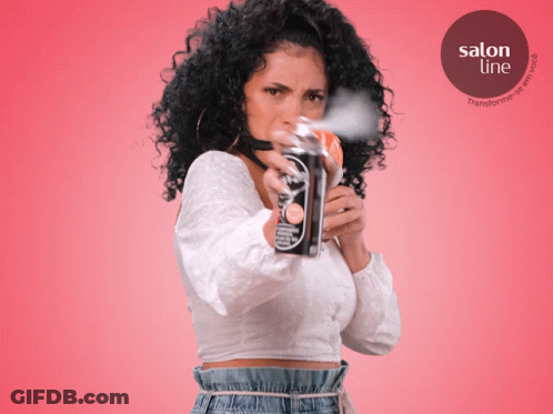 A Woman With Curly Hair Is Spraying A Can Of Salon Line GIF