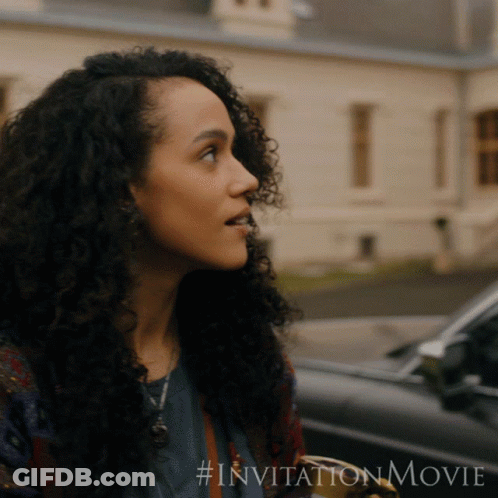 A Woman With Curly Hair Is Standing In Front Of A Car With # Invitationmovie Written On The Bottom GIF