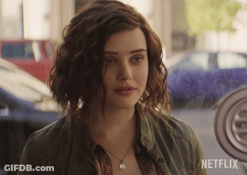 A Woman With Curly Hair Is Standing In Front Of A Netflix Logo GIF