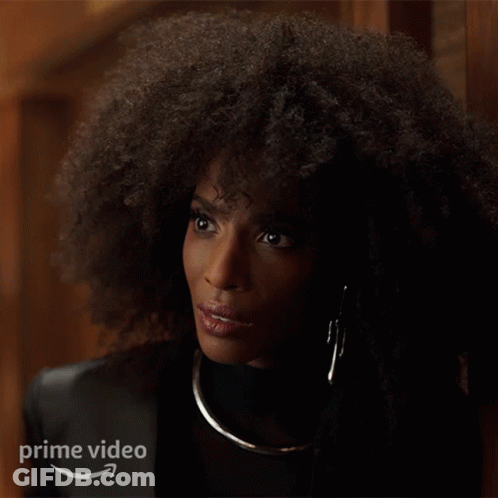 A Woman With Curly Hair Is Standing In Front Of A Sign That Says " Prime Video " GIF