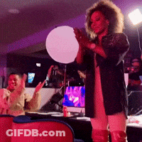 A Woman With Curly Hair Is Standing In Front Of A White Ball GIF