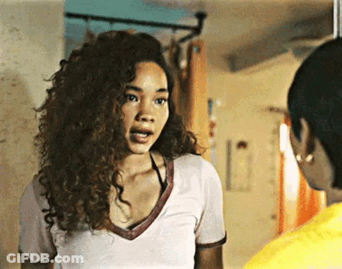 A Woman With Curly Hair Is Standing Next To Another Woman In A Room . GIF