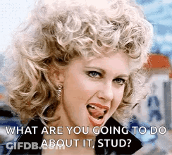 A Woman With Curly Hair Is Sticking Her Tongue Out And Asking What Are You Going To Do About It , Stud . GIF