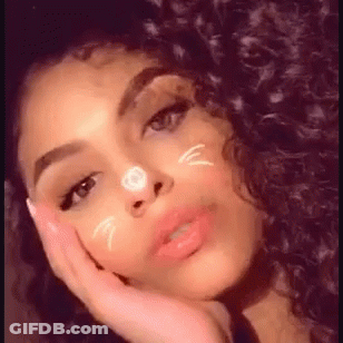 A Woman With Curly Hair Is Taking A Selfie With Her Hand On Her Face And A Cat Face On Her Face . GIF