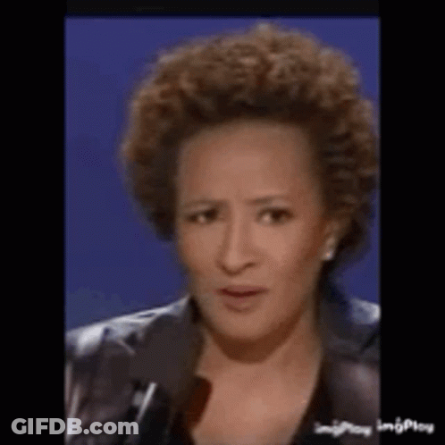 A Woman With Curly Hair Is Talking Into A Microphone . GIF