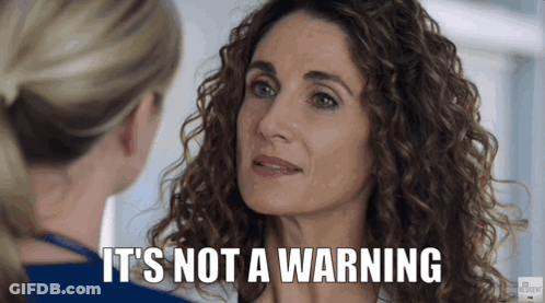 A Woman With Curly Hair Is Talking To Another Woman Who Says It 'S Not A Warning . GIF