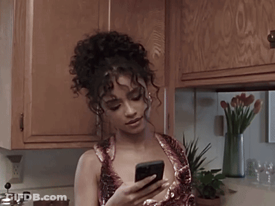 A Woman With Curly Hair Is Using A Cell Phone GIF
