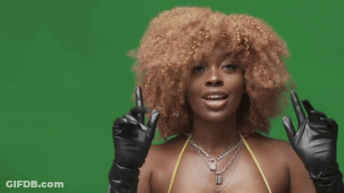 A Woman With Curly Hair Is Wearing A Bikini Top And Black Gloves . GIF