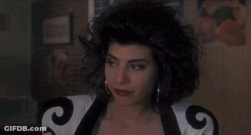 A Woman With Curly Hair Is Wearing A Black And White Jacket With The Letter G On It . GIF