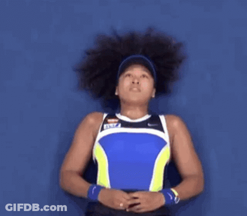 A Woman With Curly Hair Is Wearing A Blue And Yellow Tank Top GIF