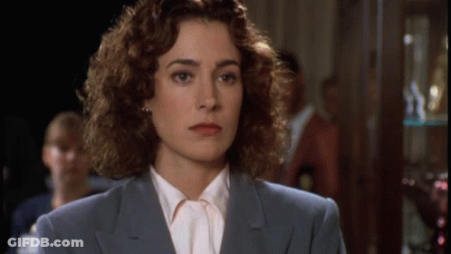 A Woman With Curly Hair Is Wearing A Blue Suit And A White Shirt GIF