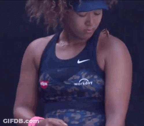 A Woman With Curly Hair Is Wearing A Blue Tank Top And A Hat . GIF