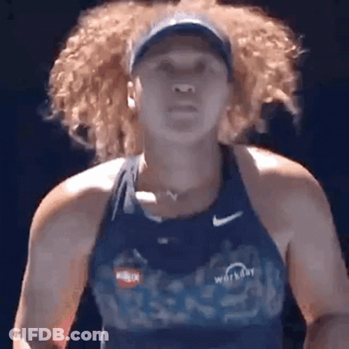 A Woman With Curly Hair Is Wearing A Blue Tank Top And A Hat While Playing Tennis . GIF