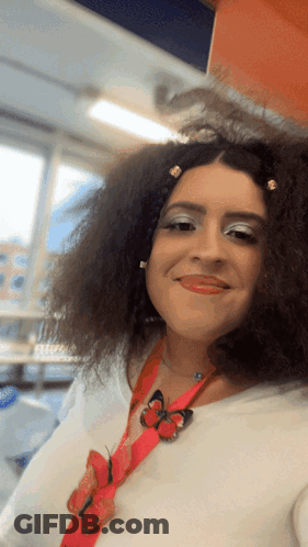 A Woman With Curly Hair Is Wearing A Red Lanyard With Butterflies On It GIF