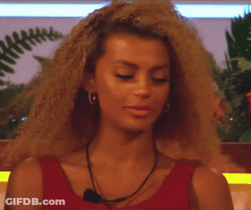 A Woman With Curly Hair Is Wearing A Red Top GIF
