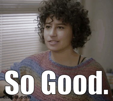 A Woman With Curly Hair Is Wearing A Sweater With The Words So Good Written On It GIF