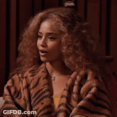 A Woman With Curly Hair Is Wearing A Tiger Print Sweater GIF