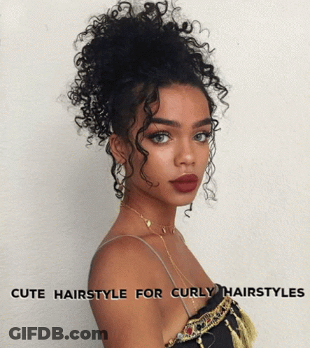 A Woman With Curly Hair Is Wearing A Top And A Necklace GIF