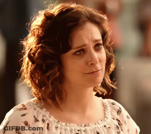 A Woman With Curly Hair Is Wearing A White Top With A Floral Print GIF