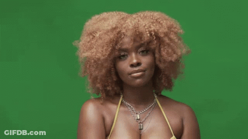 A Woman With Curly Hair Is Wearing A Yellow Bikini Top And A Necklace On A Green Screen . GIF