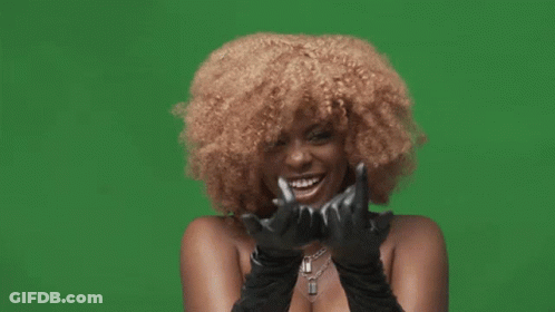 A Woman With Curly Hair Is Wearing Black Gloves And Making A Rock And Roll Sign GIF