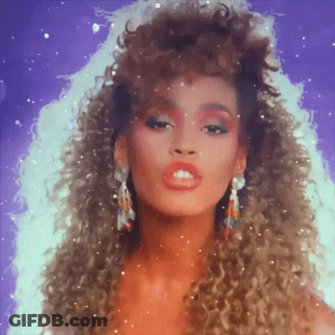 A Woman With Curly Hair Is Wearing Earrings And Red Makeup GIF