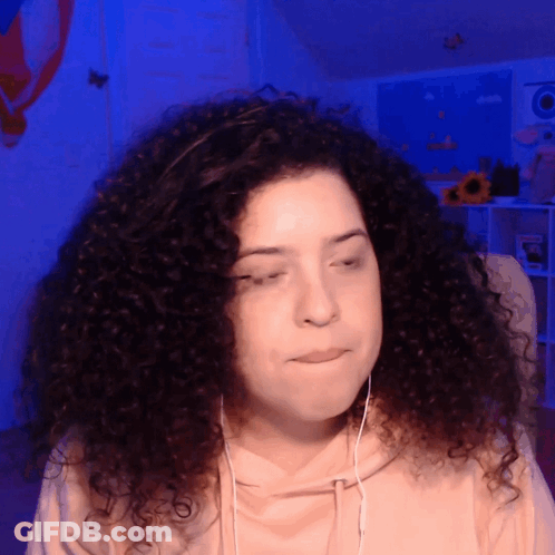 A Woman With Curly Hair Is Wearing Headphones And Making A Sad Face GIF