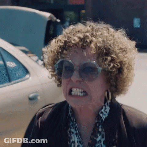 A Woman With Curly Hair Is Wearing Sunglasses And A Leopard Print Shirt . GIF