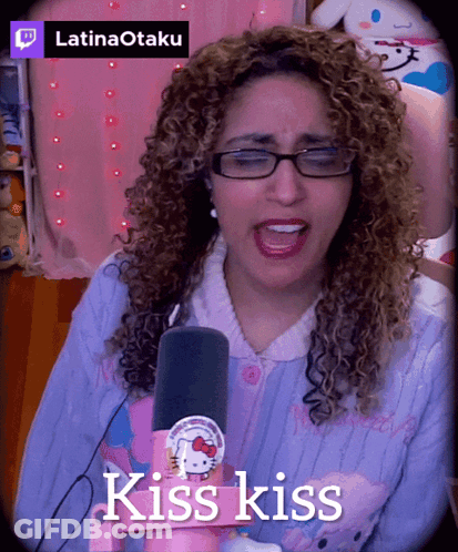 A Woman With Curly Hair Singing Into A Microphone With The Words Kiss Kiss Above Her GIF