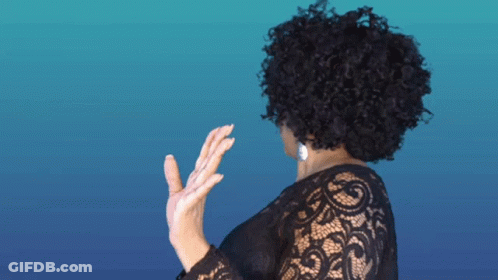 A Woman With Curly Hair Wearing A Black Lace Shirt GIF