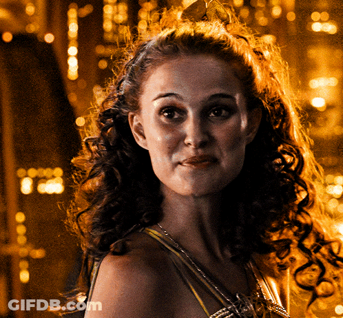 A Woman With Curly Hair Wearing A Crown Looks At The Camera GIF