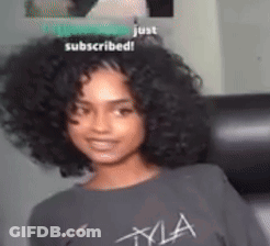A Woman With Curly Hair Wearing A Gray T-Shirt That Says Kyla GIF
