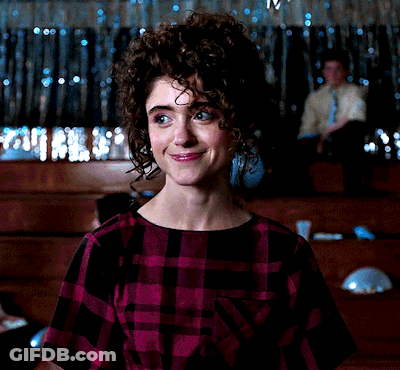 A Woman With Curly Hair Wearing A Purple Plaid Shirt GIF