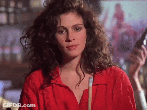 A Woman With Curly Hair Wearing A Red Shirt Holds A Pool Cue GIF