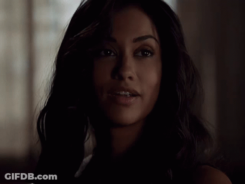 A Woman With Dark Hair Is Smiling In The Dark GIF