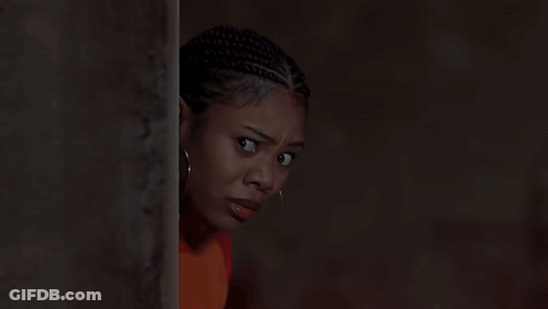 A Woman With Dreadlocks And Hoop Earrings Is Leaning Against A Wall GIF