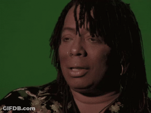 A Woman With Dreadlocks Is Making A Funny Face In Front Of A Green Screen GIF