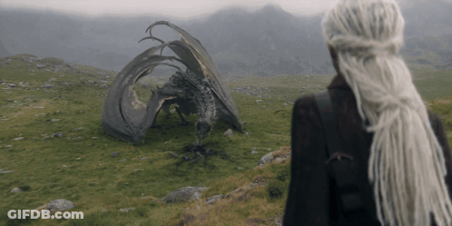 A Woman With Dreadlocks Stands In Front Of A Fallen Dragon GIF