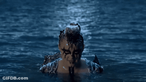 A Woman With Face Paint Is Swimming In The Water At Night GIF
